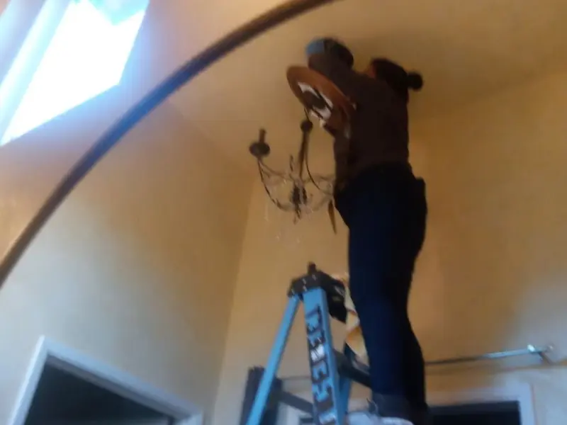 Electrician installing a chandelier in a Folsom residence